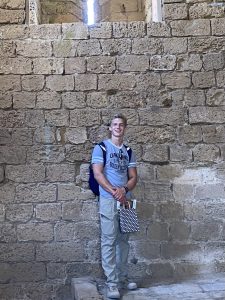Photo of Lucas standing in front of a brick wall