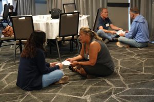 People sit on the ground and participate in a tissue paper activity at the event