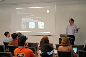 Corey presents in front of a crowded room